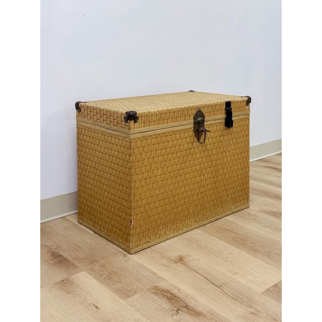 This vintage woven chest showcases a light, blonde wicker finish paired with distinctive brass clamp hardware, offering a...
