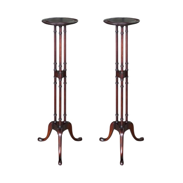 A pair of elegant plant stands, circa 1940, crafted of solid mahogany and featuring Regency inspired stylized faux bamboo...