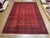 Vintage hand-knotted Afghan Bokhara rug with a red field covered in repeating elephant foot gul motifs and geometric...
