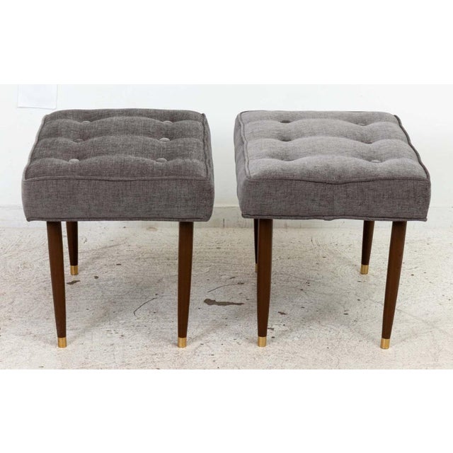 Pair of Mid Century Benches. Newly upholstered with buttons and seaming. Featuring walnut legs with brass sabots. Good...