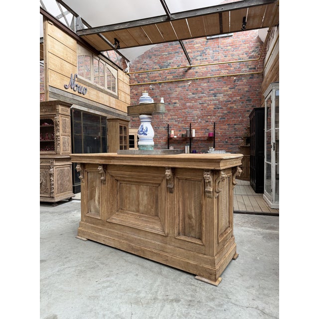 This antique firwood bar counter has been fully restored. Its front and sides are adorned with carved wooden chimeras. The...
