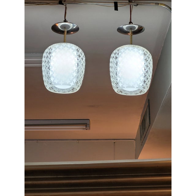 Pair of vintage Lightolier 1960's pendant lamps. Frosted outer glass shade with a pattern of transparent cross motifs....