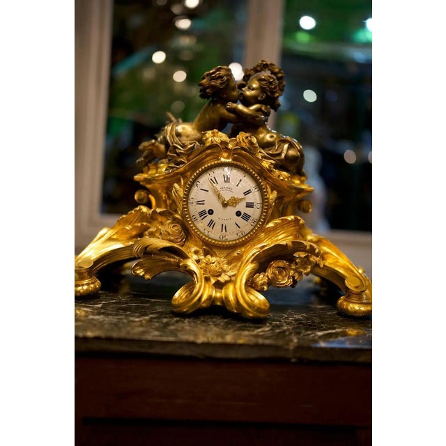 Louis XV style 19th century French figural gilt bronze mantel clock. The enamel dial with Roman numerals and foliate...