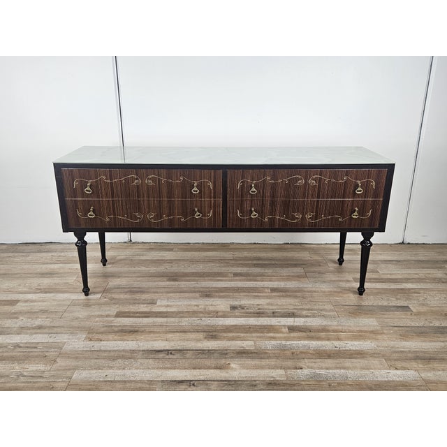 Italian furniture with four large drawers decorated with brass handles and workmanship along the fronts. Note the...
