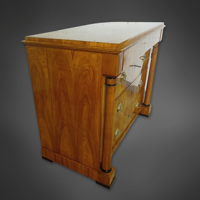 A beautiful Biedermeier chest of drawers, circa 1840, crafted from various hardwoods with cherry veneer. The veneer has a...