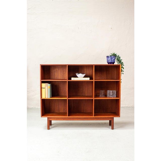 with its clean lines, warm teak wood, and slender base, this bookcase strongly evokes the designs of Peter Hvidt. Crafted...