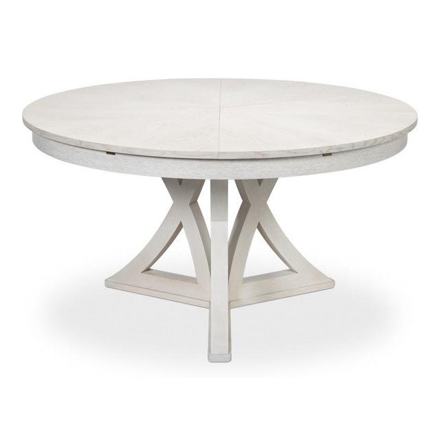 A pale circular top rests over an open geometric base, giving the table scale without enclosing the space beneath it. Four...