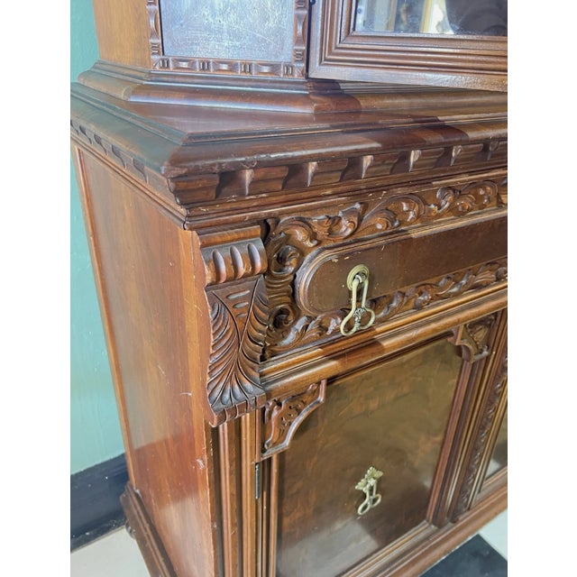 Gorgeous ornate carved wood hutch featuring glass doors, unique two finger brass pulls, floral embossed brass knob, and...