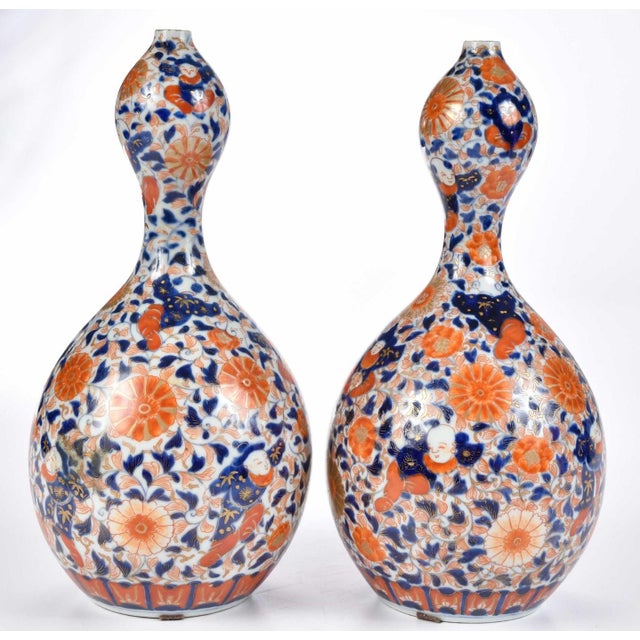 underglaze blue with orange enameling, figures amongst flowers, gilt blue signatures to base, 12 in.