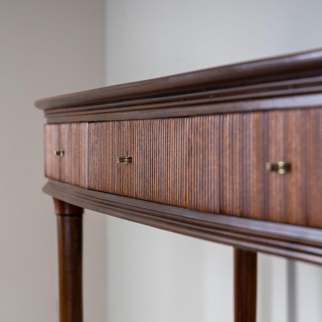 Mid-Century console table standing on tapered legs with brass caps. The piece features a ribbed surface, three drawers,...