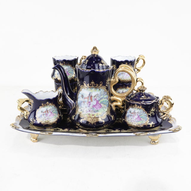 This exquisite vintage cobalt blue porcelain tea set features intricate gold detailing and a charming hand-painted...