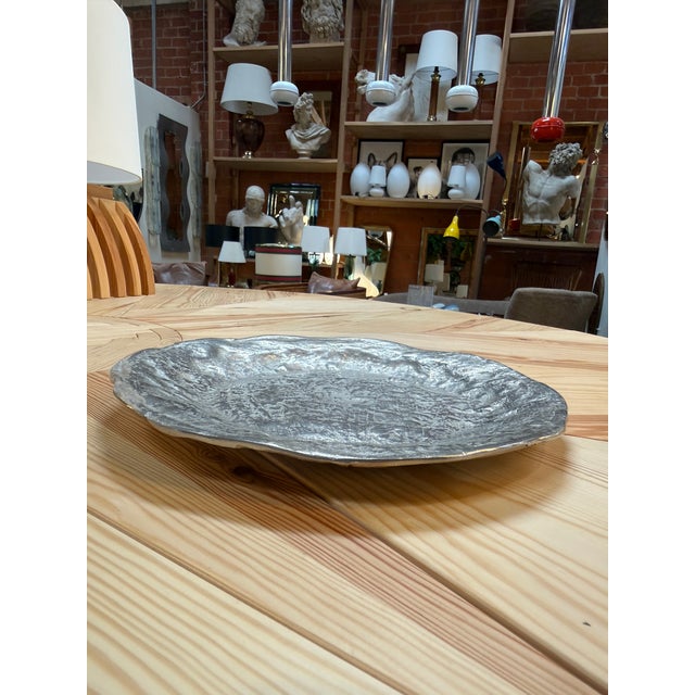 A sculptural decorative dish featuring an irregular rounded silhouette and a richly textured surface reminiscent of...