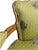 Wood-framed armchairs with curved wooden arms and legs. Covered in a light green fabric with a peacock pattern and small...