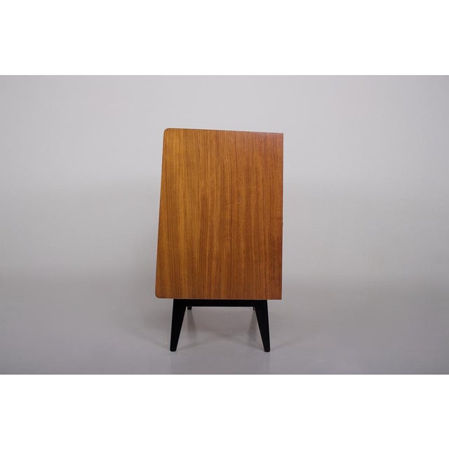 Small two-door sideboard in exotic wood (bubinga) on black lacquered beechwood compass legs. It opens with a free-form...