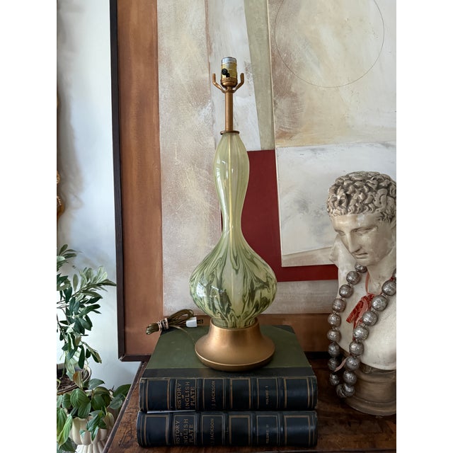 A striking mid century Italian Empoli style art glass lamp featuring a soft green and cream swirl pattern that feels both...