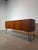A striking mid-century modern G-Plan sideboard, crafted in beautifully figured teak and elevated on elegant black hairpin...