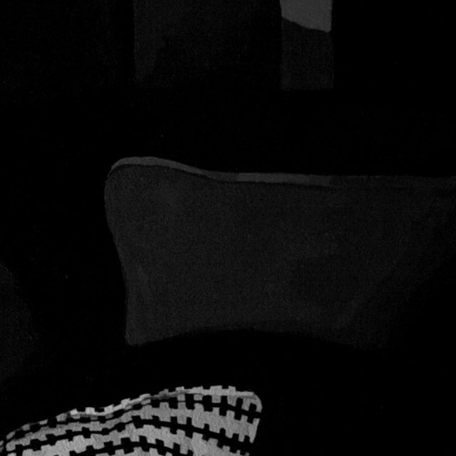 The artwork depicts a figure reclining on a plush surface, enveloped in a patterned blanket, evoking a sense of intimacy...