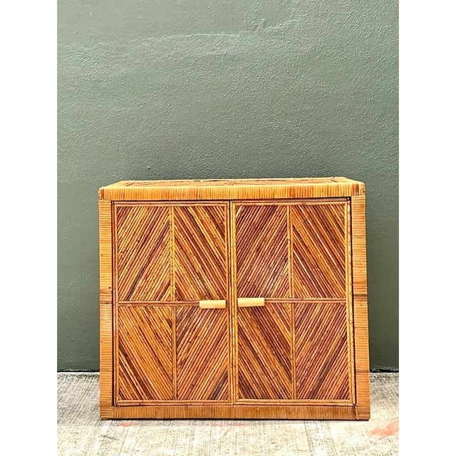 This vintage rattan chevron cabinet is a striking example of mid-20th-century woven design, its clean rectangular form...