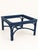 A sculptural rattan table presented in a deep navy finish, with curved rattan framework beneath a square glass top. Its...