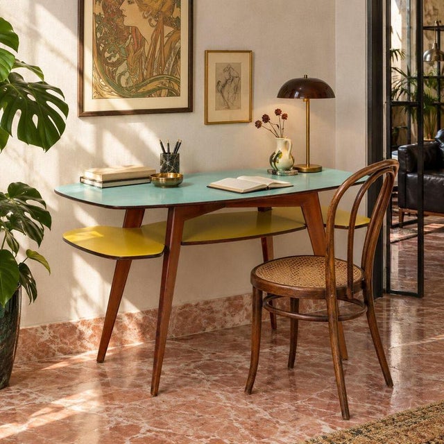 Italian 1950s desk characterized by distinctive design and functional structure. The double formica top, one blue and the...