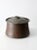 An antique hammered copper cauldron with a rounded basin, gently tapered sides, and pronounced rolled rim. The hand-...