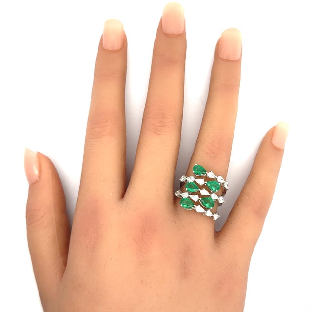 A striking contemporary cluster ring featuring 1.76 carats of pear-shaped emeralds in a strong grass green color. The...