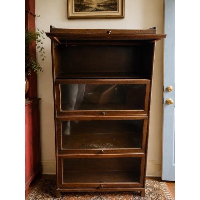 An elegant early twentieth-century oak barrister bookcase featuring four glass-front stacking sections and beautifully...