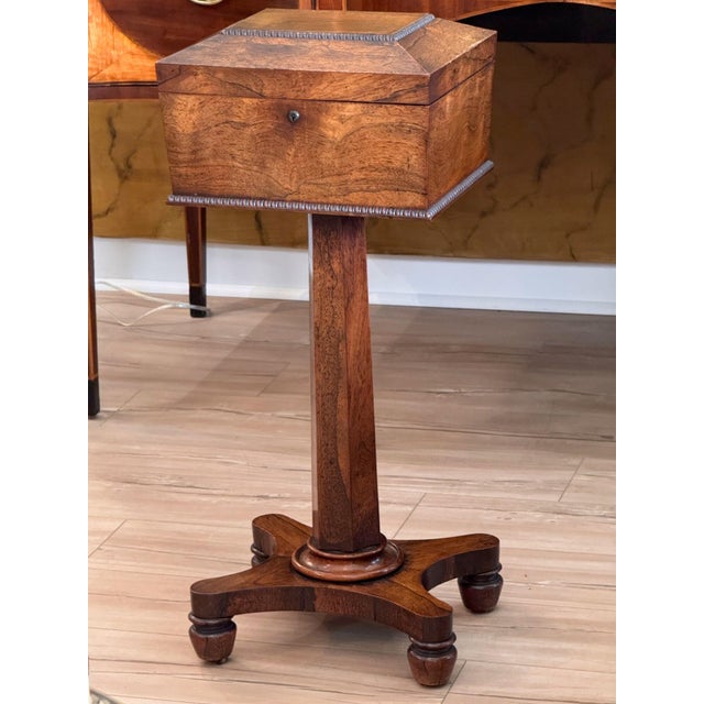 An early 19th C. English Regency rosewood teapoy with beautifully figured veneers and beaded moldings around the canted...