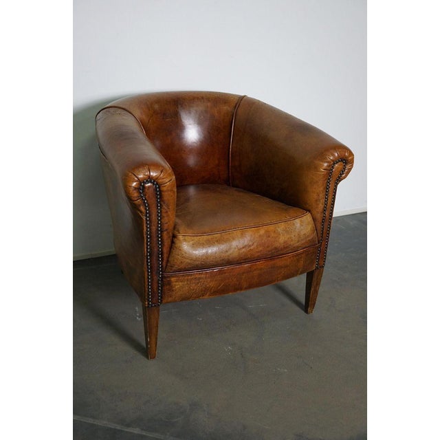This vintage cognac-colored leather club chair comes from the Netherlands. It is upholstered with cognac-colored leather...