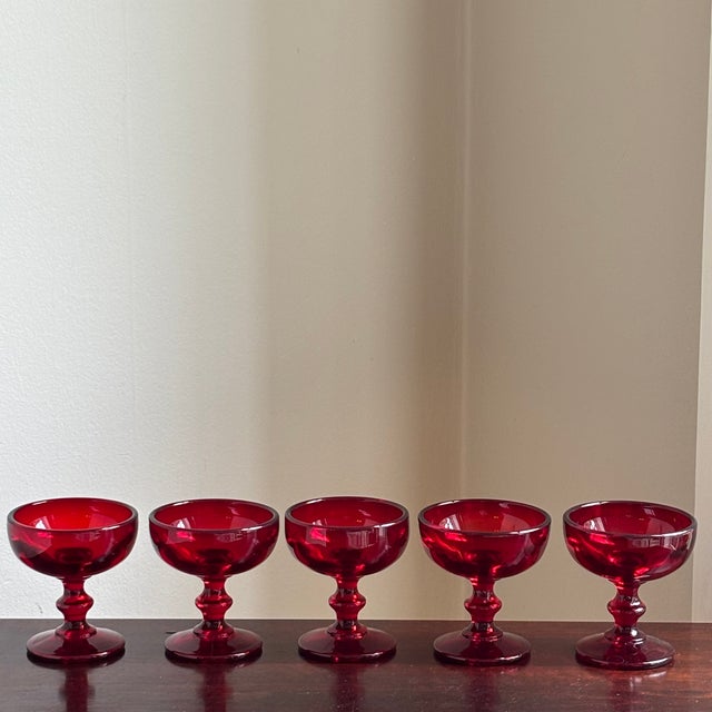 A beautiful set of five vintage ruby red glass coupe glasses featuring rich jewel-toned color and elegant pedestal stems....