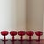 A beautiful set of five vintage ruby red glass coupe glasses featuring rich jewel-toned color and elegant pedestal stems....