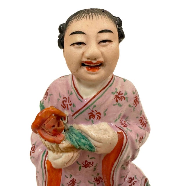 This is a vintage Chinese Famille Rose porcelain figurine of a a deity holding a flower basket with a Mark on the bottom....