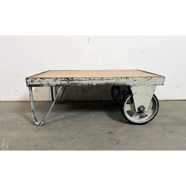 Former pallet truck from a factory now serves as a coffee table. It features a light grey iron construction with two...