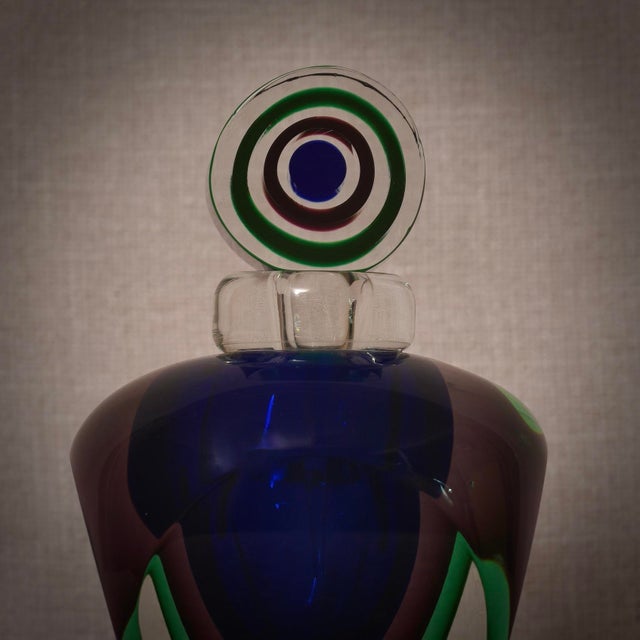 A perfume bottle with internal decorations in various shades of blue, green, and transparent. A sculpture of the highest...