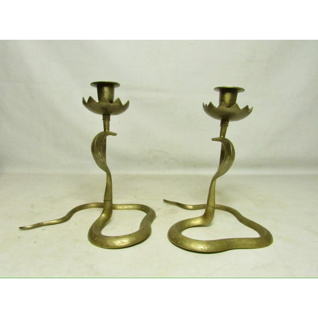 Pair of Anglo Indian brass cobra candlesticks, c1970’s. Standing on their curled tails with their heads raised and holding...