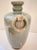 A rounded celadon vessel with a short, gently flared neck and two ring-style handles set into molded mounts on either...