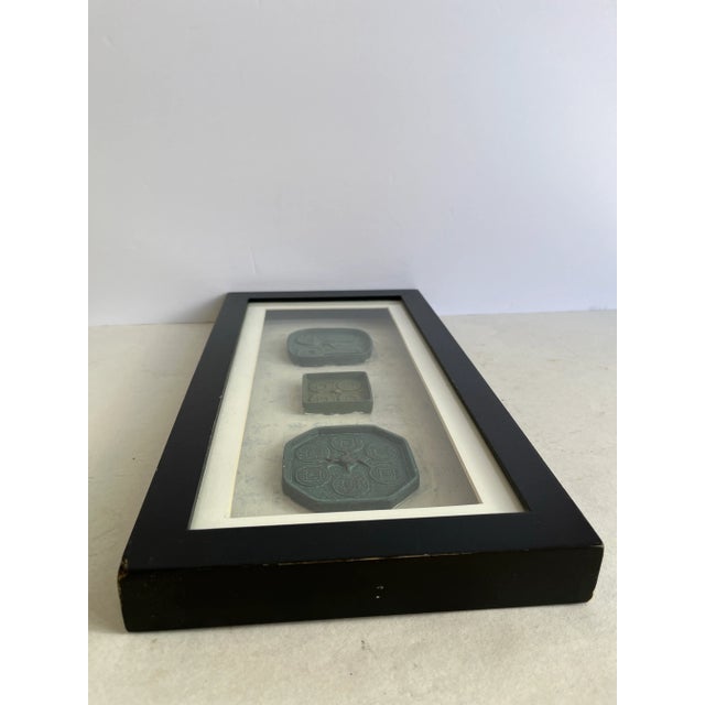 Set of three Chinese coin or stamp style molds mounted and finished with glass and black painted wood shadow box frame.