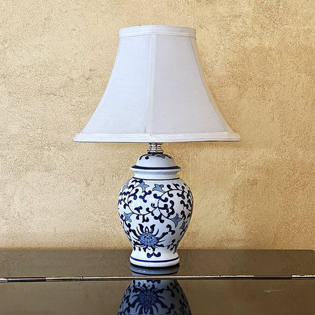 This charming vintage Chinoiserie-style table lamp features a classic blue and white porcelain ginger jar base decorated...