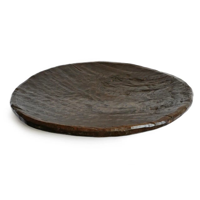 Large hand-carved wooden platter from the Tharu region of Nepal, likely used for communal serving or food preparation....