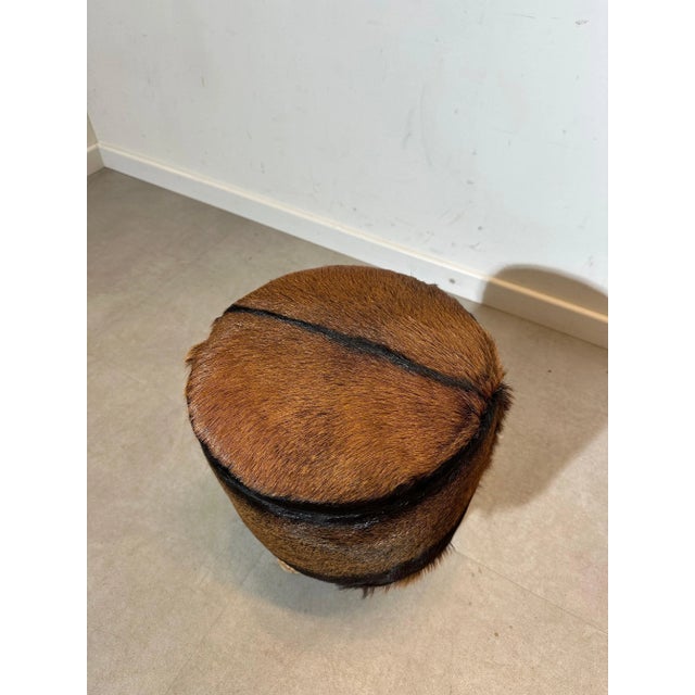 Charming vintage stool featuring a rustic, natural look. The seat is upholstered in genuine brown and black cowhide,...