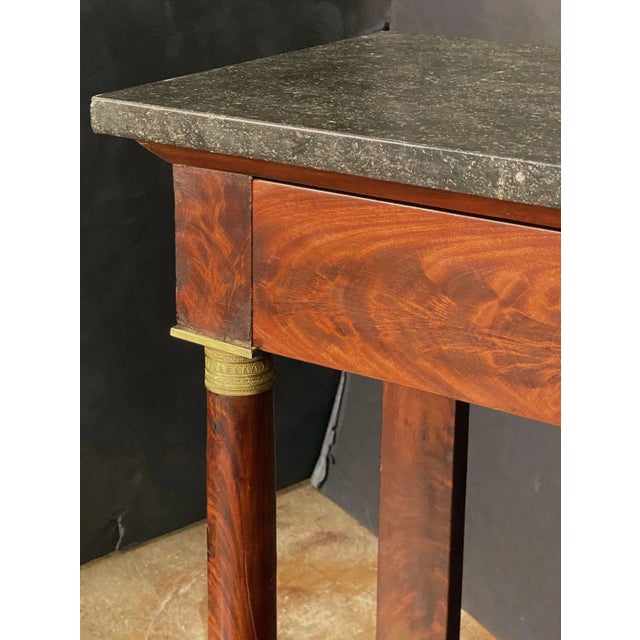 A handsome French Empire console table of fine proportions, featuring a rectangular figured marble top, set upon a frieze...