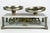 An antique French balance scale by Rafael M. Volpi with brass pans and an ornately engraved mechanism visible through...