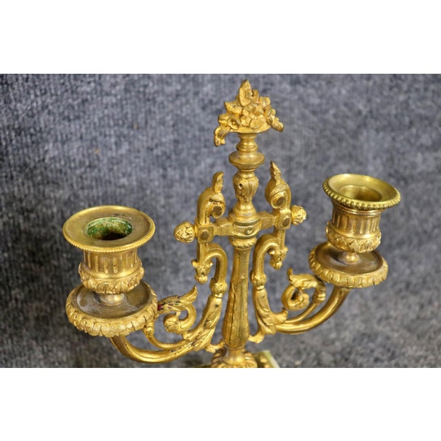 Bronze. Marble. 3 piece. Mantel set. Clock measures 14" h x 9 1/2" w x 4" d. Candelabras measure 10 1/4" h x 7 3/8" w x 3...