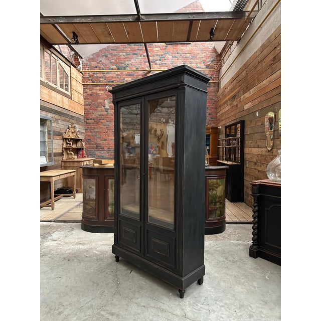 This antique black patina display cabinet has been fully restored. It has two large glass doors with their original bubble...