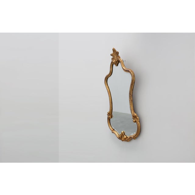 An elegant Italian Florentine-style mirror dating from the 20th century, distinguished by its gracefully shaped silhouette...