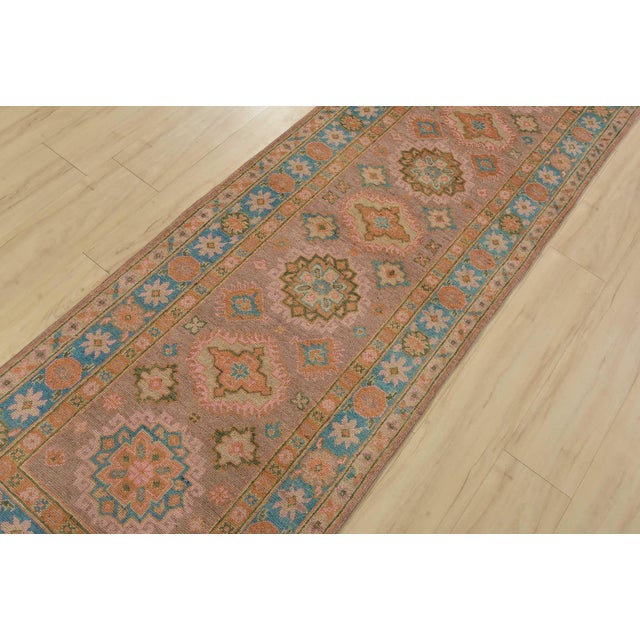 A tribal Caucasian Kazak runner hand-knotted with fine wool on a cotton foundation. This rug features a row of geometric...