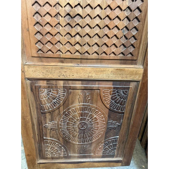 Bring artistic detail and the warmth of natural wood into your home with this hand-carved teak wood barn door, featuring a...