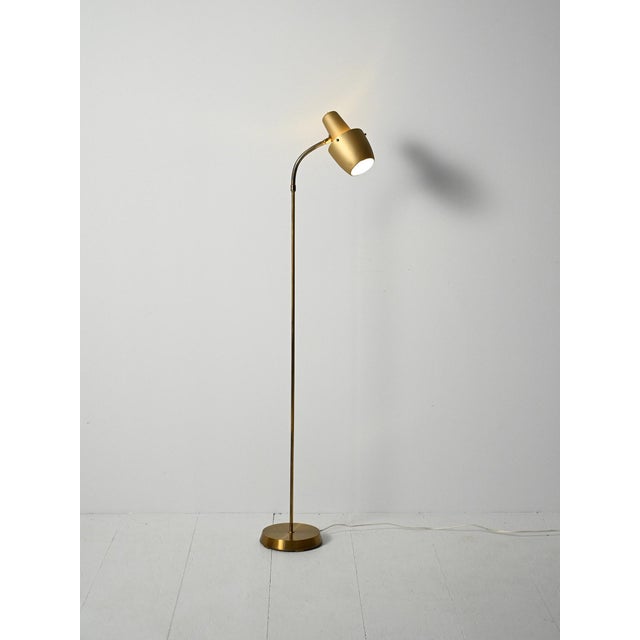 Floor lamp in brass and gold-plated metal, with a round base and adjustable gooseneck arm; tapered head with anti-glare...