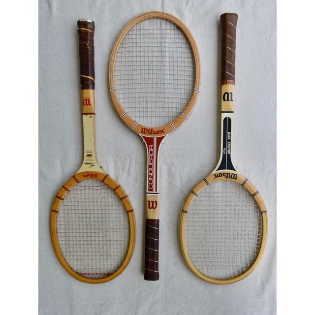A charming set of three vintage Wilson wooden tennis racquets, each accompanied by its original wooden racquet press....