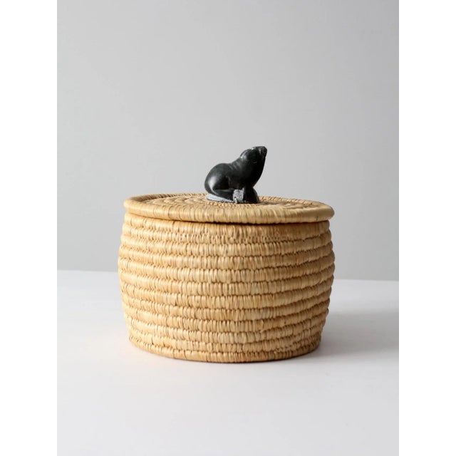 Vintage woven basket with lid featuring a softly hued grassy-reed construction and a beautifully rounded bowl form. The...